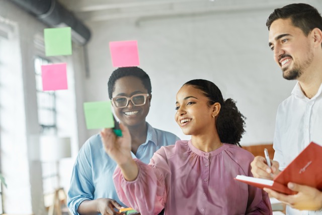 Business people meeting at office and using sticky notes on glass to share idea.