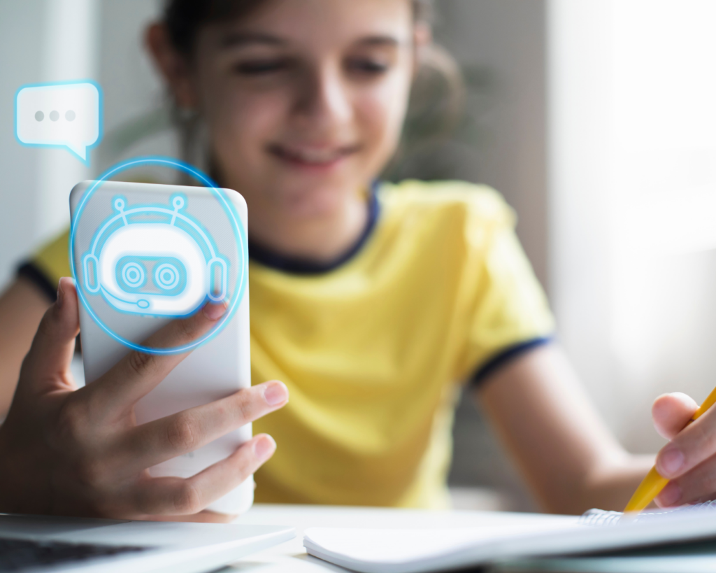 A young student does her homework at a table while holding up a smartphone. A graphical representation of a robot face is overlaid on the smartphone.